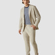 Model in full body wearing a Tech Linen Blazer Sandshell with a striped t-shirt underneath and with matching pants