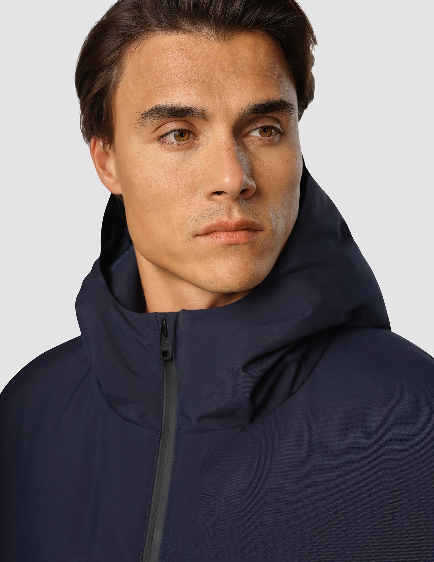 A person wearing a dark navy Utility Jacket with a zippered hood.