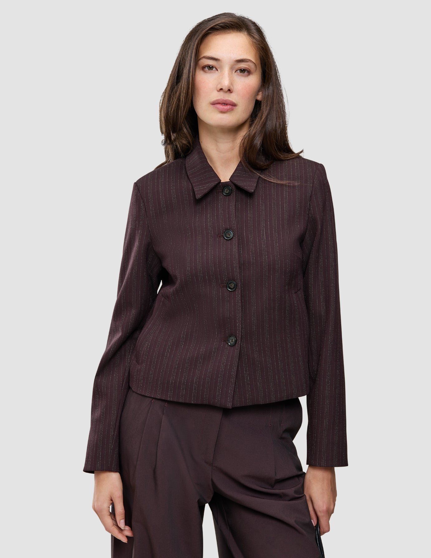 A woman wears the Burgundy from top to toe set, featuring a dark burgundy pinstriped button-down jacket and matching trousers.