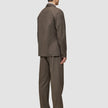 A man viewed from behind, wearing an Atelier Overshirt Dark Beige and matching trousers in a Scandinavian design.