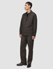A person wearing a heavyweight, textured dark brown Atelier Overshirt and matching trousers over a black shirt.