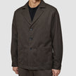 A person wearing an Atelier Overshirt Dark Brown, a Scandinavian-designed blazer with notch lapels, three buttons, and two large patch pockets.