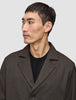 A man wears an Atelier Overshirt Dark Brown made of heavyweight textured fabric over a black crew neck shirt in a Scandinavian design.