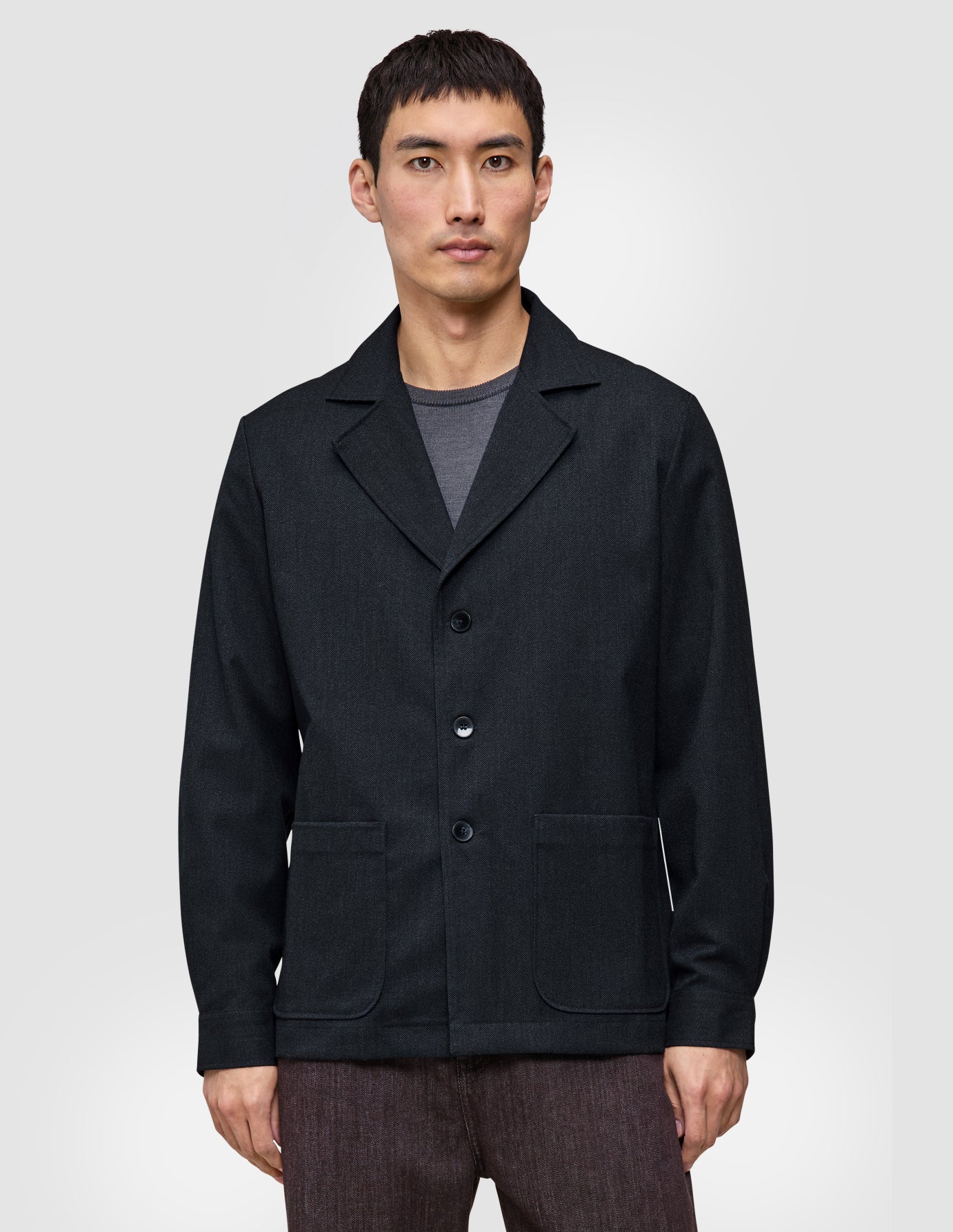 A man wearing an Atelier Overshirt in dark navy, featuring a heavyweight textured fabric, a notched collar, and two front patch pockets.