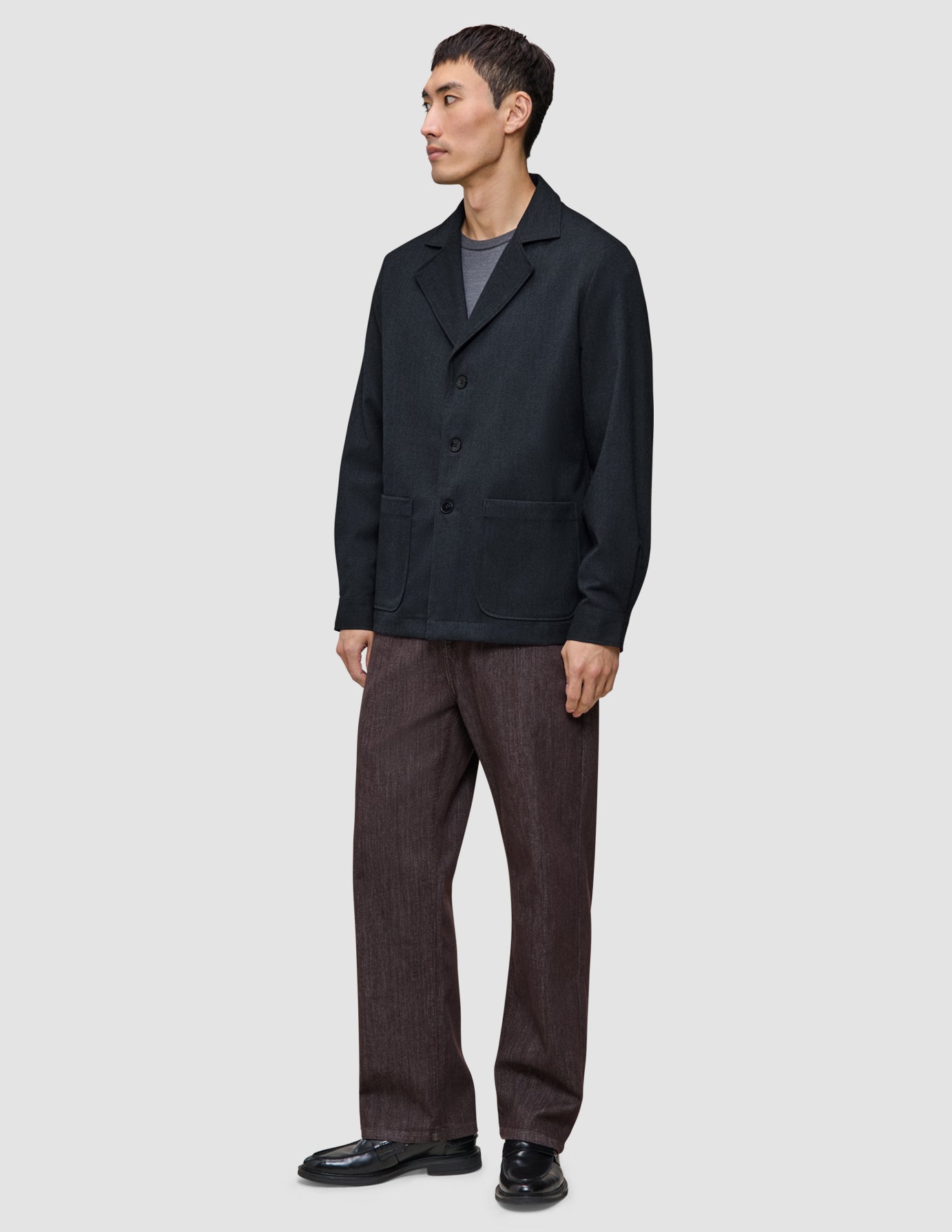A person wearing a heavyweight, textured Atelier Overshirt Dark Navy over a grey t-shirt, paired with brown trousers and black loafers.