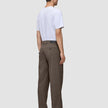 A man seen from behind wearing a white t-shirt and Atelier Pants Relaxed Dark Beige in heavyweight broken twill with black shoes.