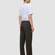 A man viewed from the side, wearing a white t-shirt and Atelier Pants Relaxed Dark Brown in heavyweight broken twill.