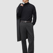 A man wearing a black turtleneck and Atelier Pants Relaxed Dark Grey in heavyweight broken twill, holding a coat over his shoulder.