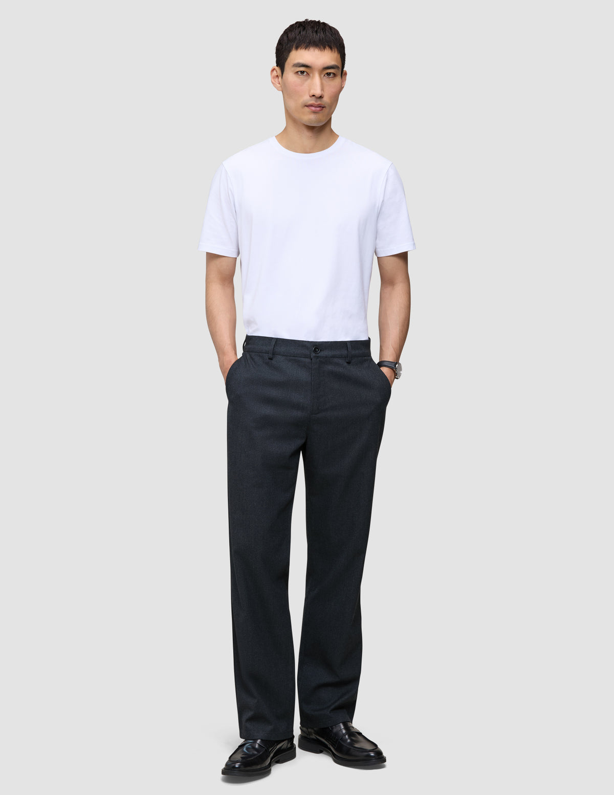 A person wearing a white t-shirt and Atelier Pants Relaxed Dark Navy with their hands in their pockets.