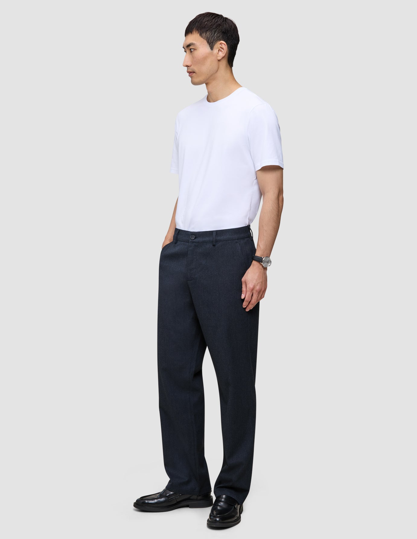 A man wearing a white t-shirt and Atelier Pants Relaxed Dark Navy, which are relaxed-fit, heavyweight broken twill trousers.