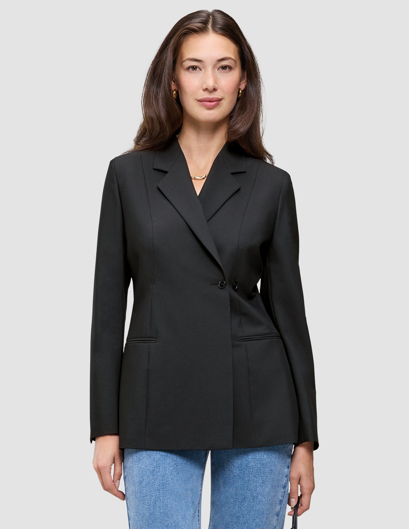 A woman wearing a black double-breasted Women’s Avira Blazer Black over blue jeans.