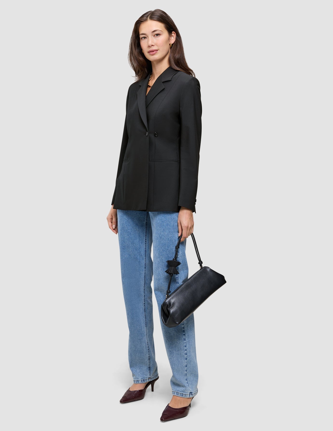 Woman wearing a Women’s Avira Blazer Black in a double-breasted design with blue jeans and a black shoulder bag.