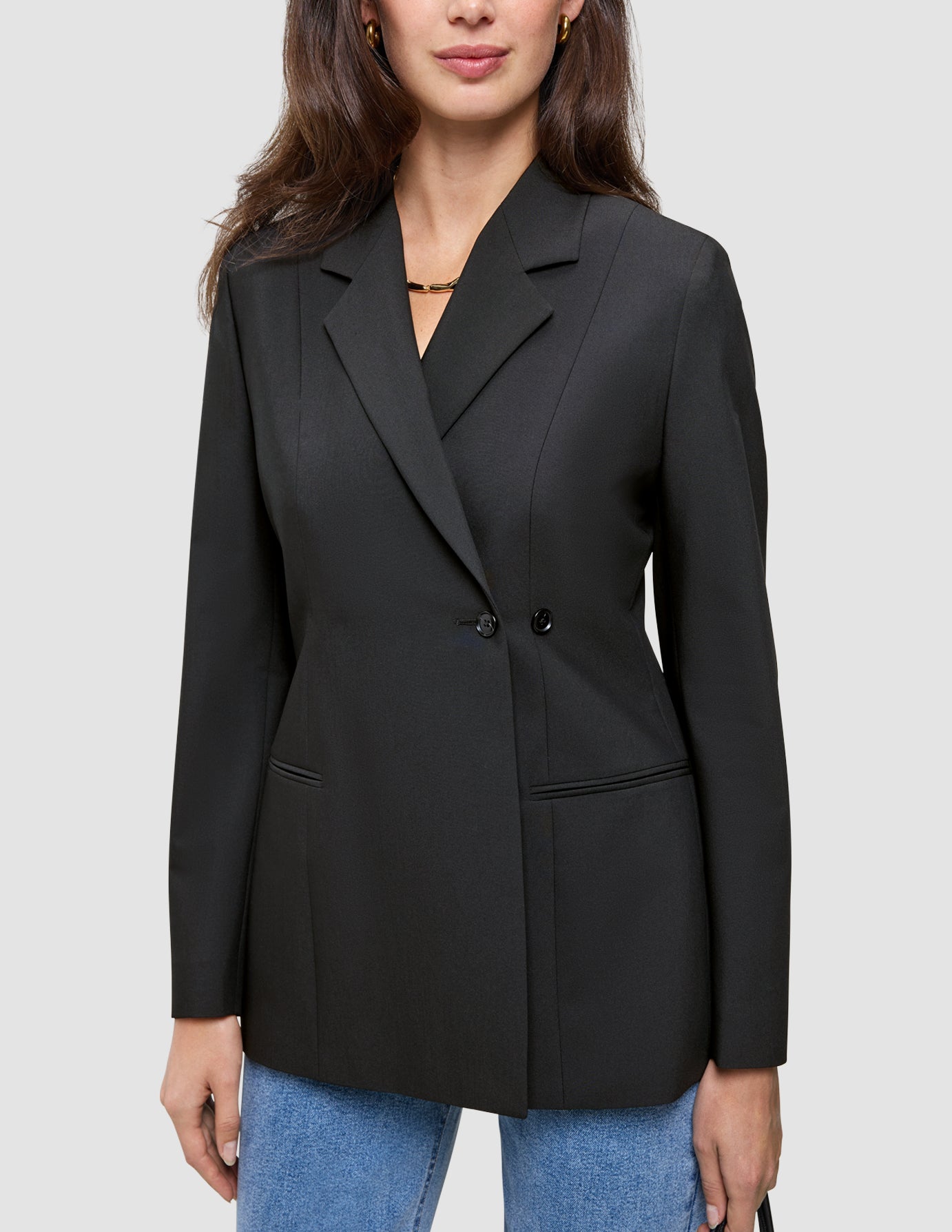A person wearing a black double-breasted Women’s Avira Blazer over blue jeans.