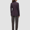 A person viewed from behind, wearing a dark burgundy double-breasted Women’s Avira Blazer Burgundy Berry and dark trousers.