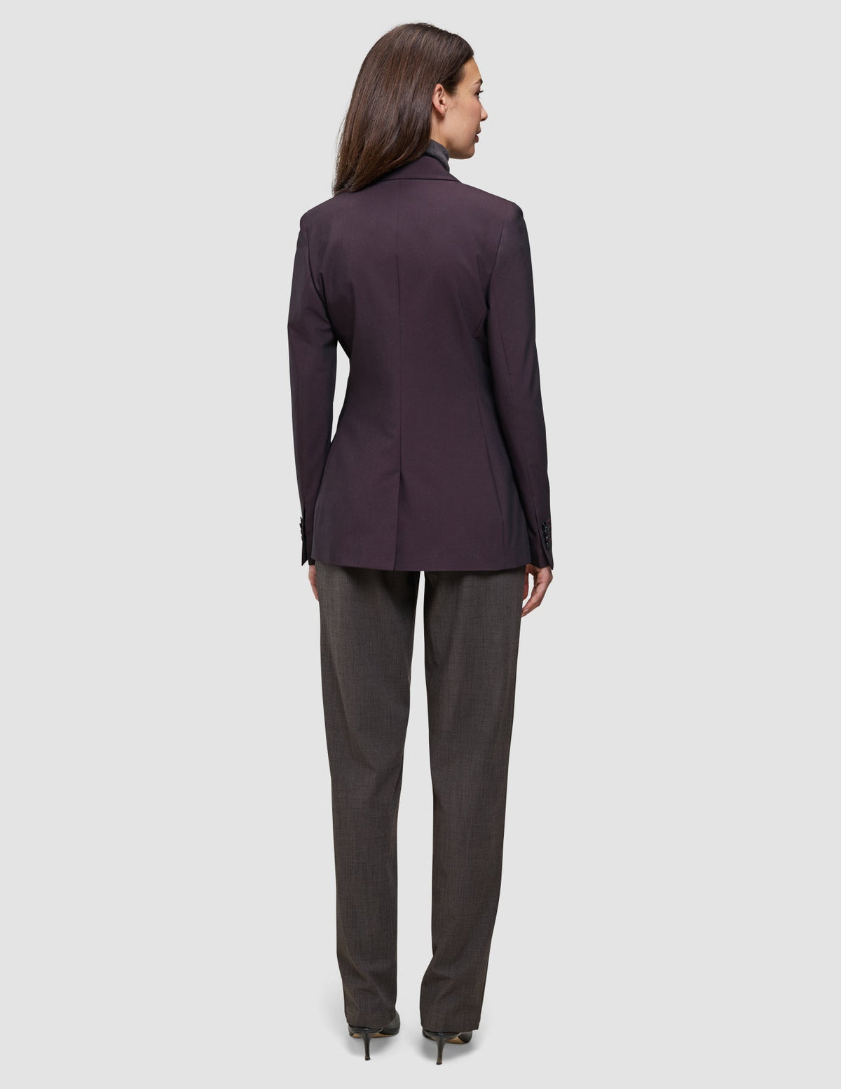 A person viewed from behind, wearing a dark burgundy double-breasted Women’s Avira Blazer Burgundy Berry and dark trousers.