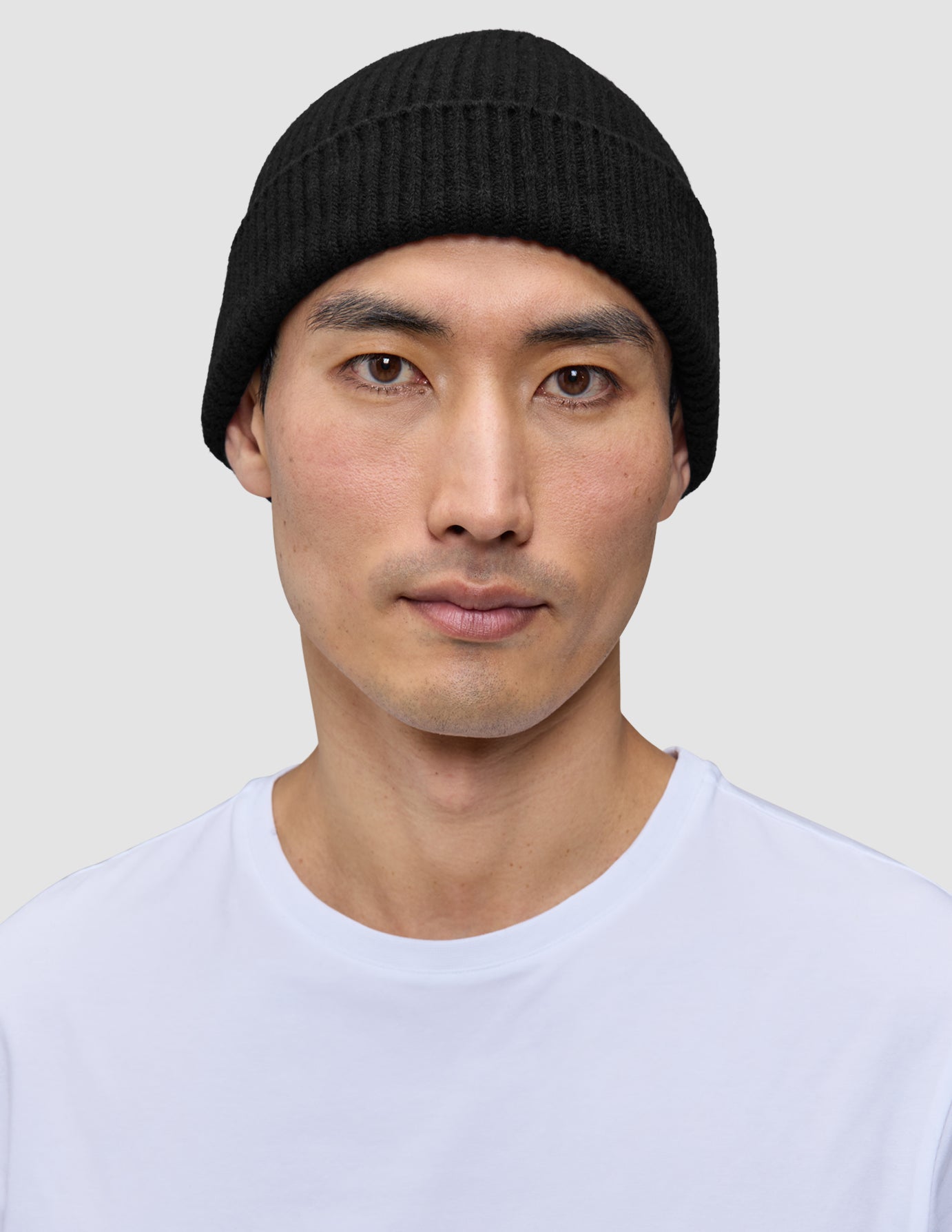 A person wearing a black merino wool rib knit Beanie Black.