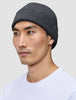 A man wearing a dark grey merino wool rib knit Beanie Dark Grey.