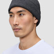 A man wearing a dark grey merino wool rib knit Beanie Dark Grey.