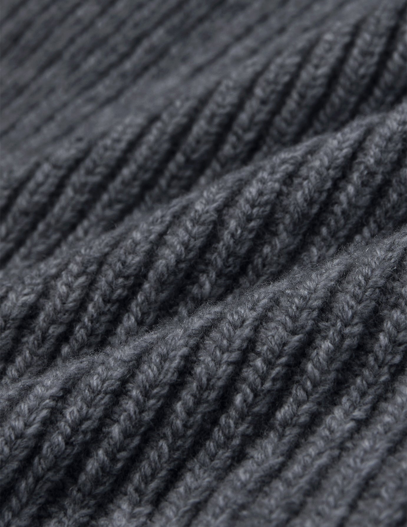 Close-up of a Beanie Dark Grey in merino wool with a rib knit and folded texture.