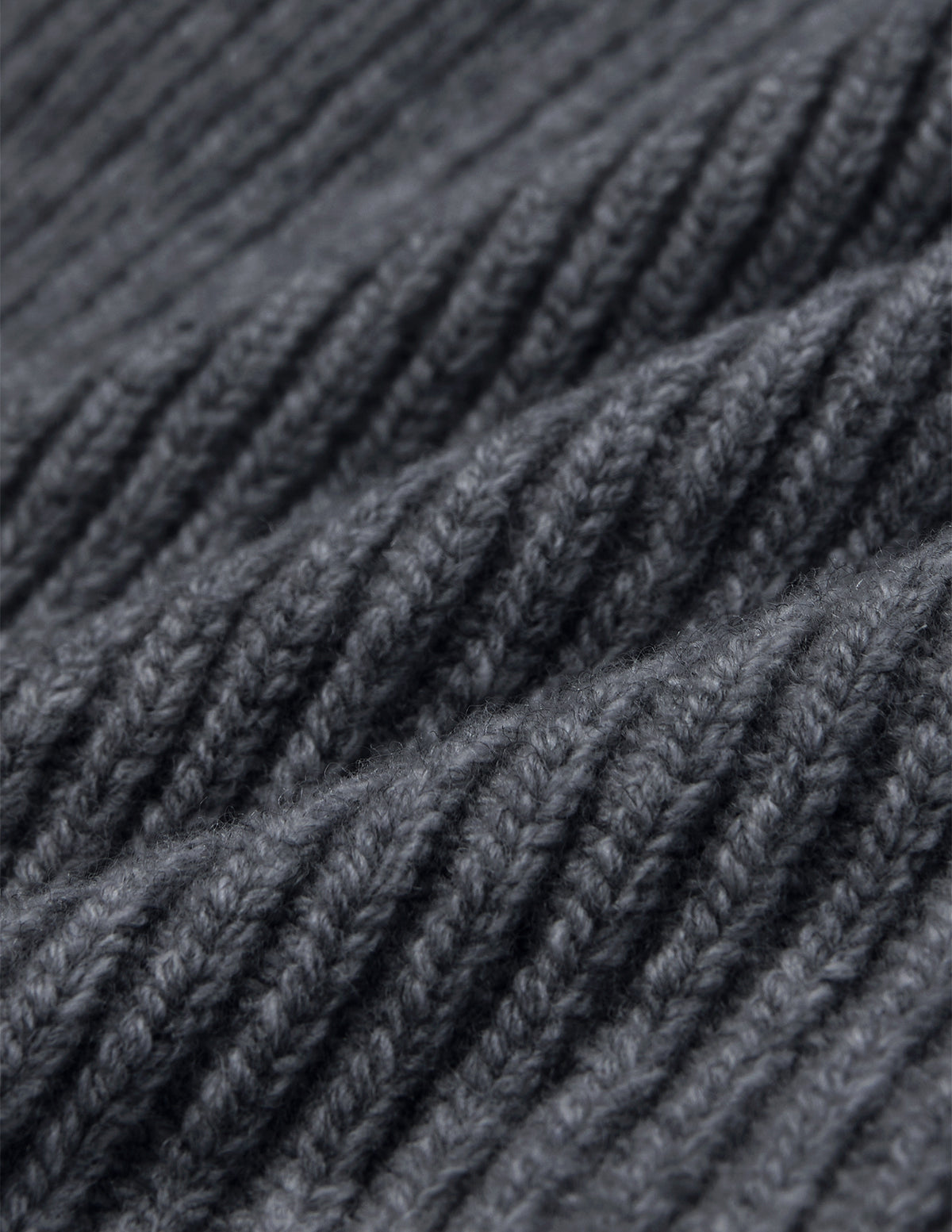 Close-up of a Beanie Dark Grey in merino wool with a rib knit and folded texture.