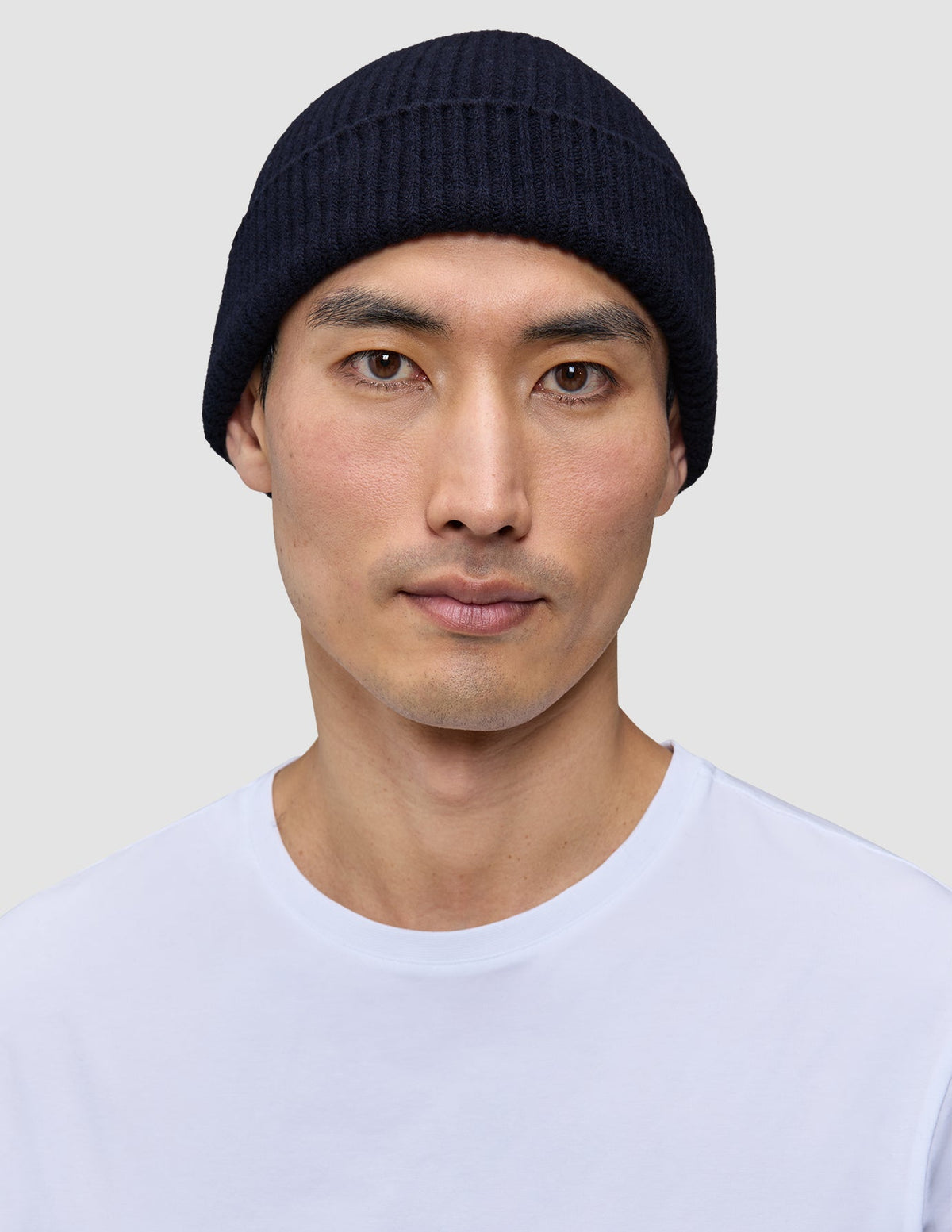 A man wearing a Wool Beanie Navy, a navy blue merino wool rib knit beanie.