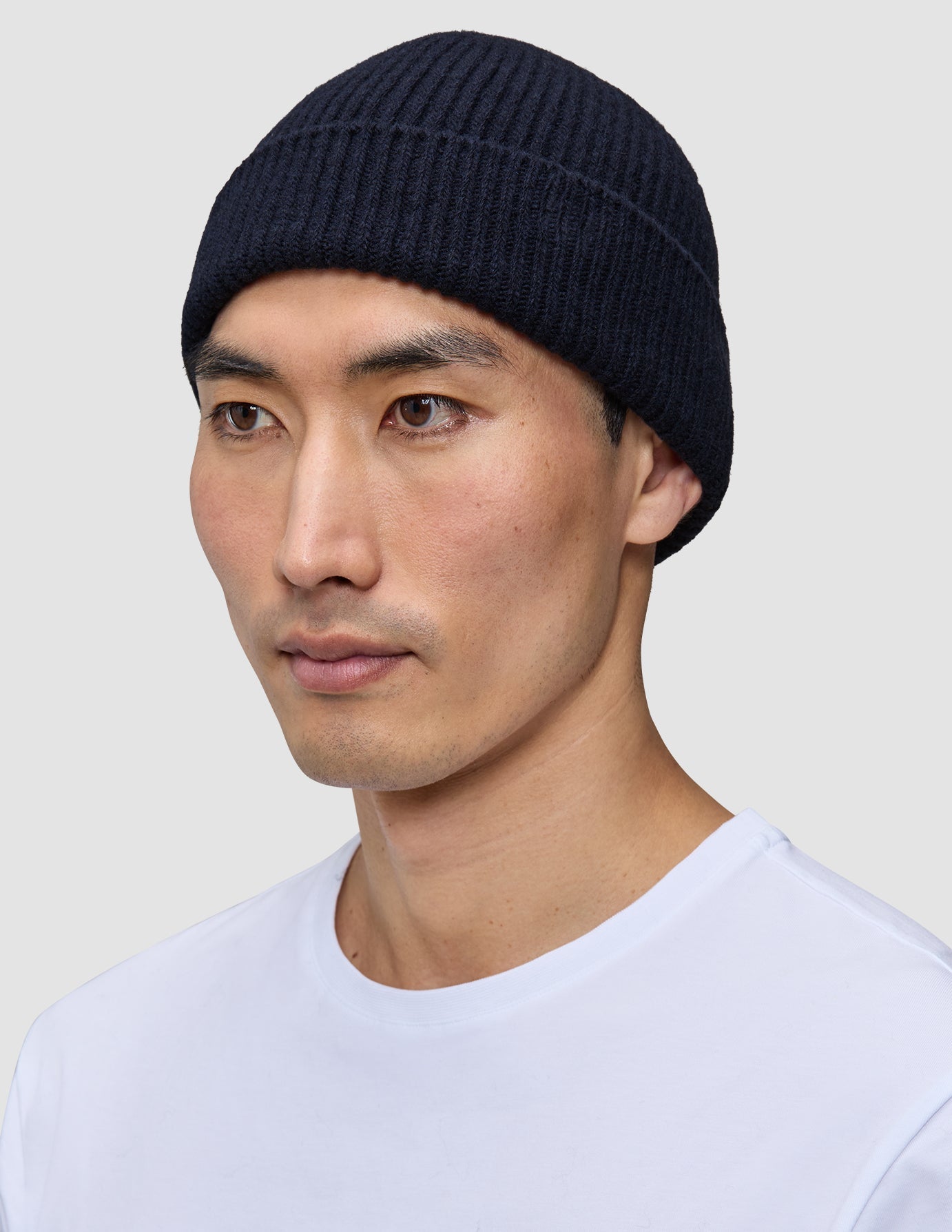 A person wearing a navy blue Wool Beanie Navy in a rib knit merino wool style.