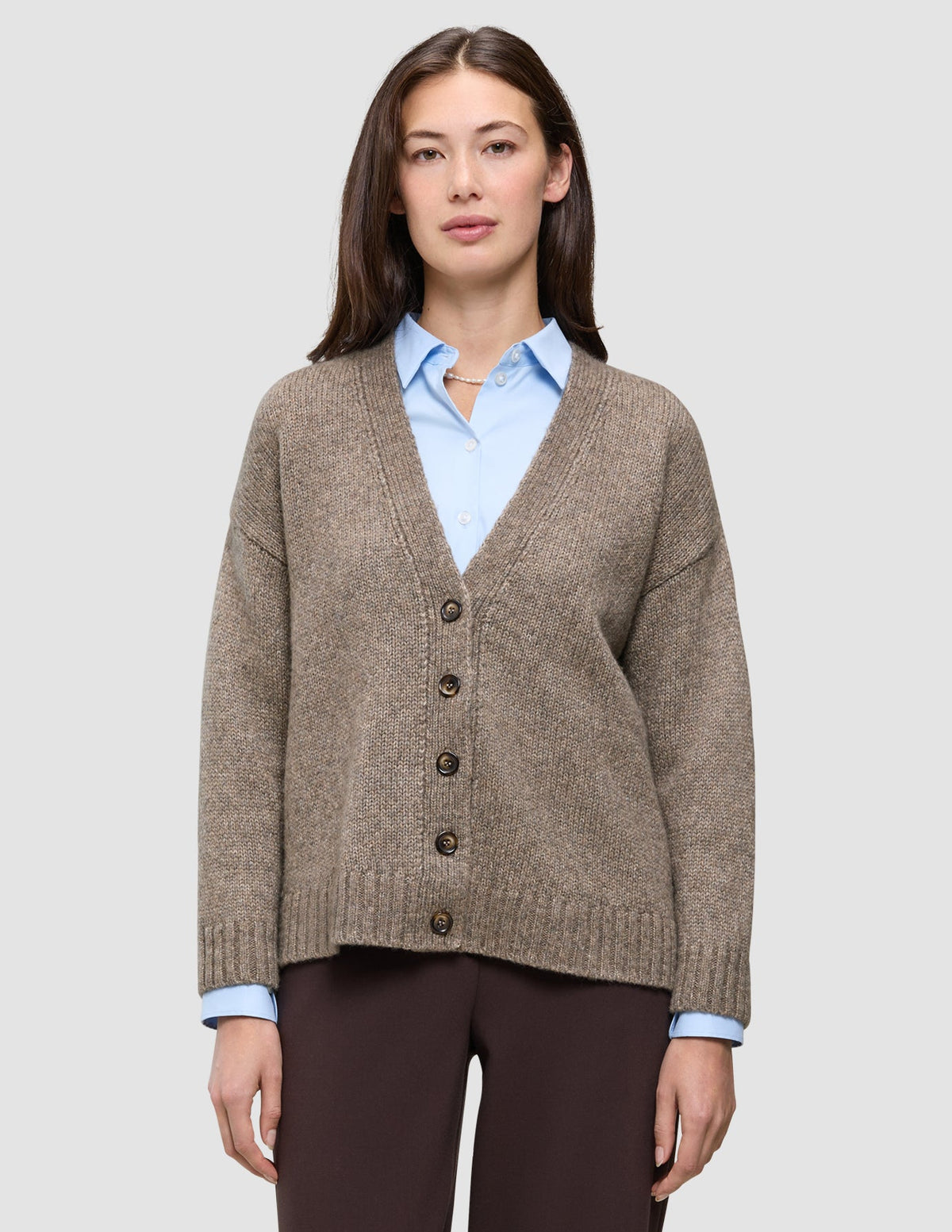 A model wears a Women’s Chunky Soft Wool Knit Cardigan Taupe Melange v-neck buttoned over a light blue collared shirt.