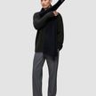 A man wearing a Chunky Soft Wool Knit Crewneck Black sweater in dark olive, grey trousers, and a black scarf draped over one shoulder.