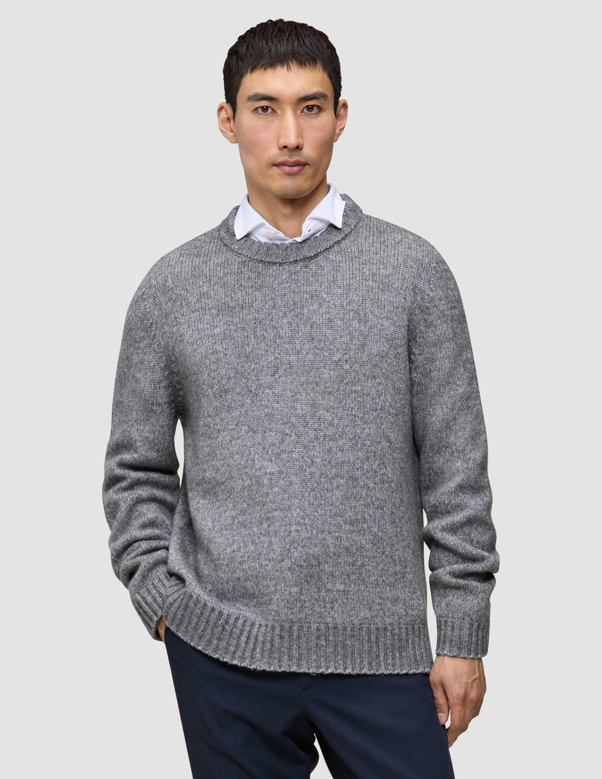 A man wearing a Chunky Soft Wool Knit Crewneck Glacier Grey sweater over a white collared shirt.