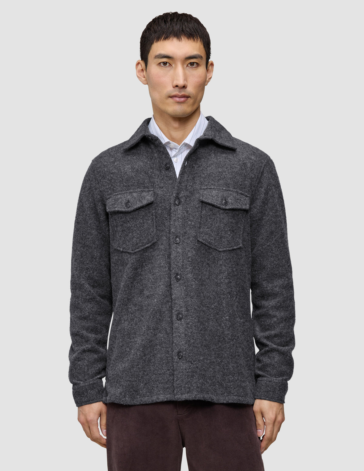 A man wearing a Double Layer Wool Overshirt Regular Dark Grey in a Scandinavian-design wool-blend with two chest pockets, layered over a white collared shirt.