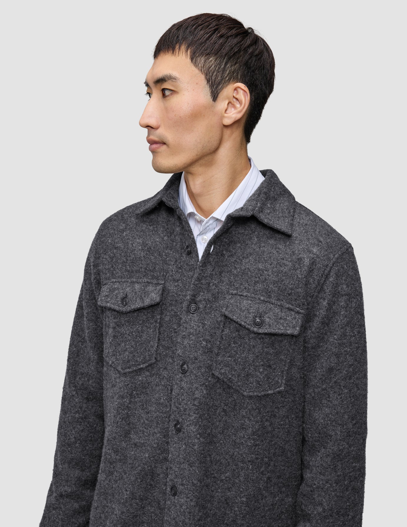 A man wearing a Double Layer Wool Overshirt Regular Dark Grey in a Scandinavian design over a white collared shirt.