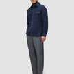 A man wears a Double Layer Wool Overshirt Regular Dark Navy over a brown turtleneck, paired with grey trousers and dark leather loafers in a minimalist Scandinavian style.