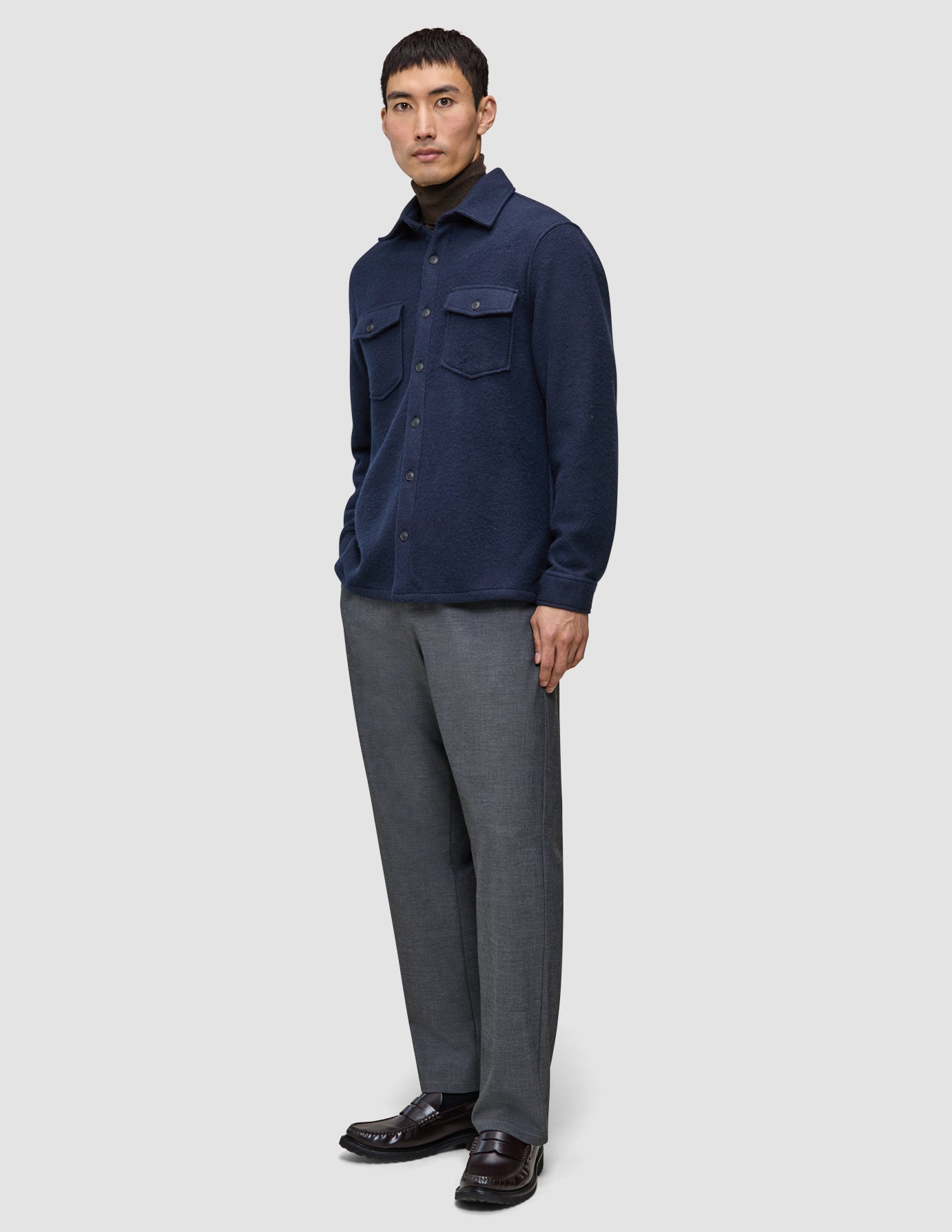 A man wears a Double Layer Wool Overshirt Regular Dark Navy over a brown turtleneck, paired with grey trousers and dark leather loafers in a minimalist Scandinavian style.
