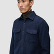 A man wearing a dark navy Double Layer Wool Overshirt Regular Dark Navy with two chest pockets over a dark brown turtleneck.