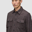 A man wears a brown Double Layer Wool Overshirt, featuring a button-up, double-layer design with two chest pockets with buttoned flaps.