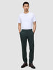 A man wearing a white t-shirt and dark green Ease Pants Regular Northern Pine with a tailored look, standing with his hands in his pockets.