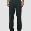 Person wearing exceptionally soft, dark green Ease Pants Relaxed Fit Northern Pine tailored trousers and dark loafers.