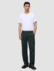 A man wearing a white t-shirt, dark loafers, and Ease Pants Relaxed Fit Northern Pine, which are exceptionally soft, dark green relaxed-fit trousers.