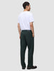 A man viewed from behind, wearing a white t-shirt and dark green Ease Pants Relaxed Fit Northern Pine with a tailored look, hands tucked into his pockets.