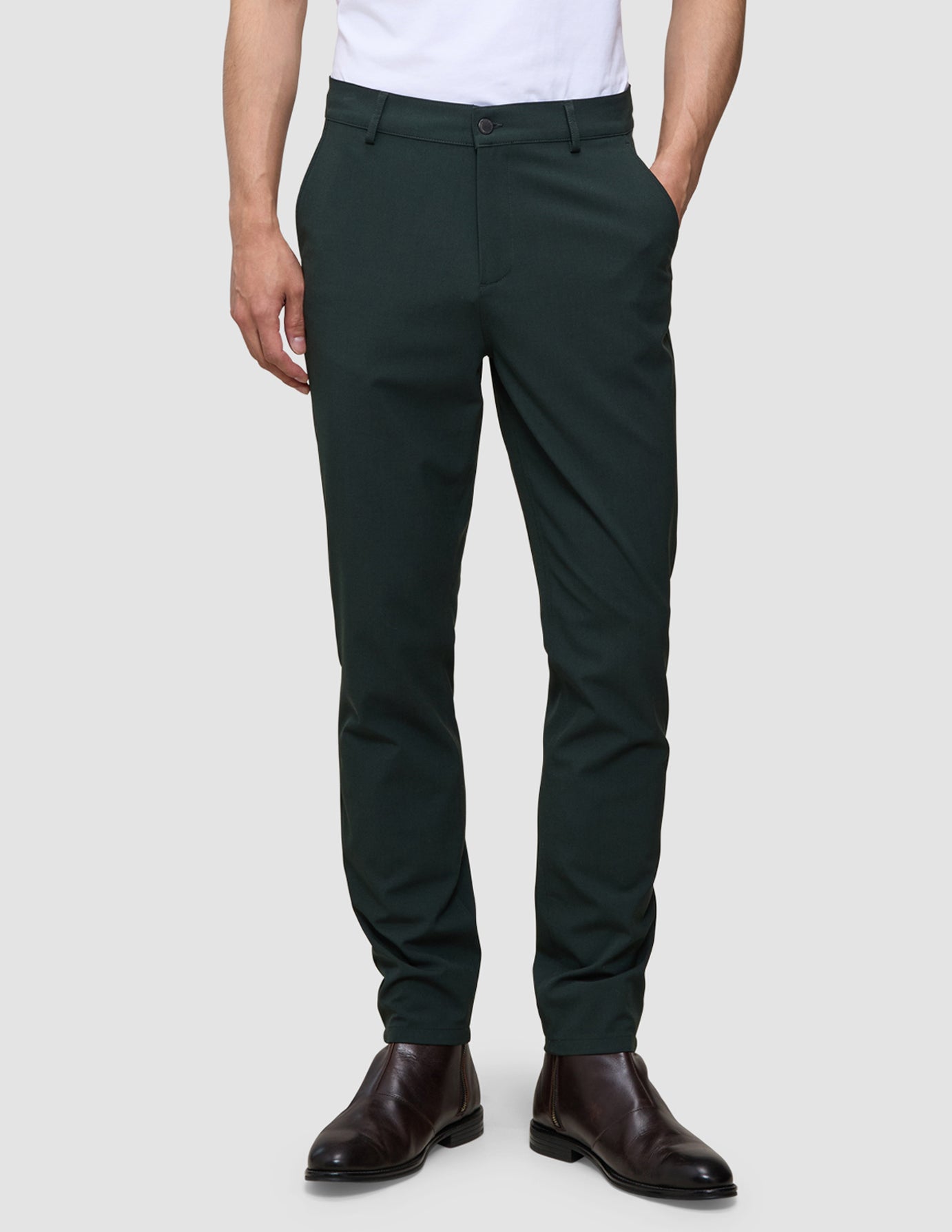 A person wearing exceptionally soft, slim-fit dark green Ease Pants Slim Northern Pine and brown leather boots.
