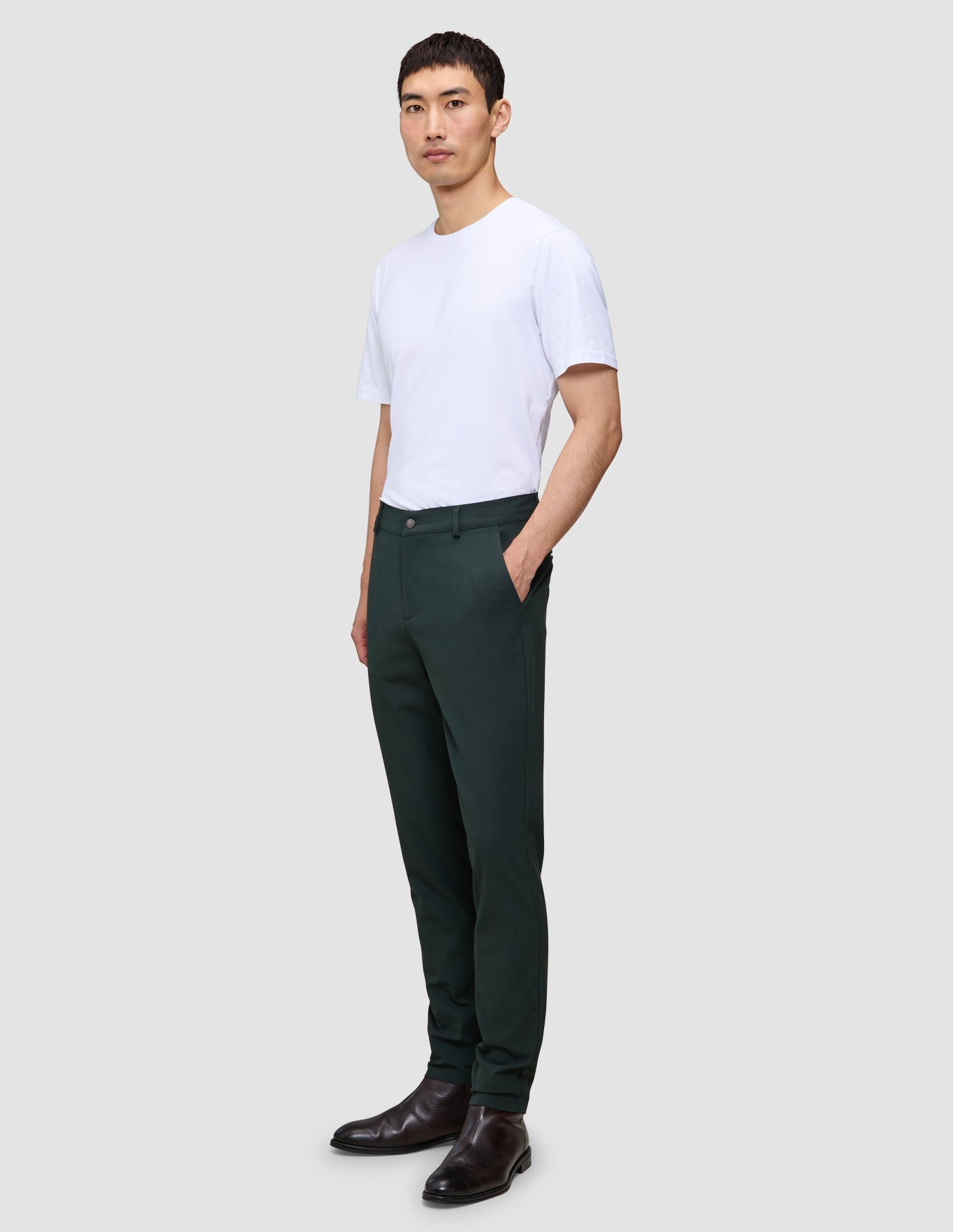 A man wearing an exceptionally soft white crew-neck t-shirt, Ease Pants Slim Northern Pine, and dark leather boots.