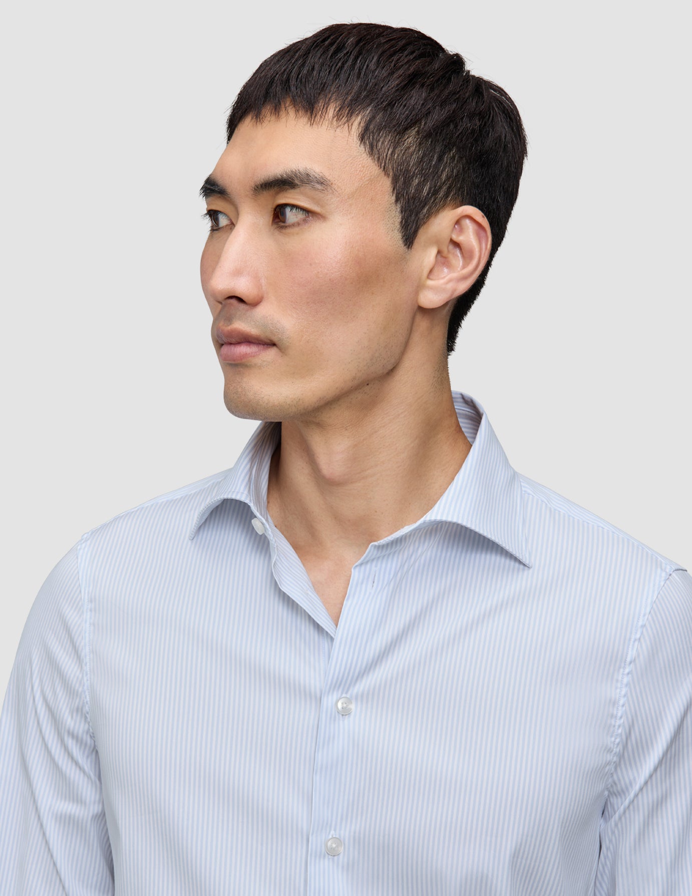 A man wearing an Elevated Shirt Regular Classic Blue Striped, an elegant, light blue and white pinstriped Pima cotton button-down shirt.