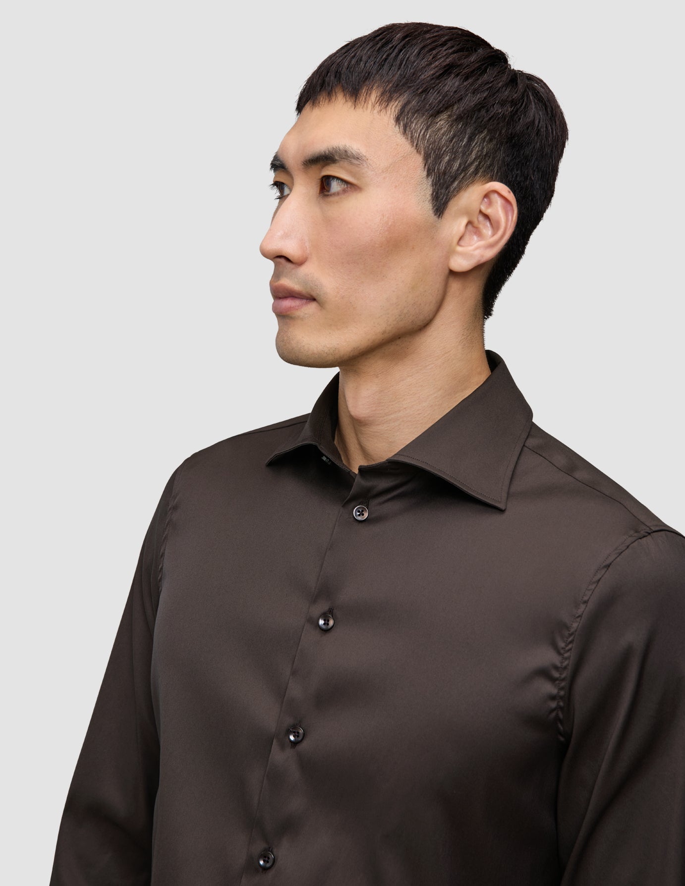 A person wearing an Elevated Shirt Regular Dark Brown, a long-sleeved Pima cotton button-down shirt.
