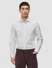 A man wearing an Elevated Shirt Slim Light Grey Striped, a light grey long-sleeved shirt with thin vertical stripes and dark trousers, reflecting a Scandinavian design aesthetic.