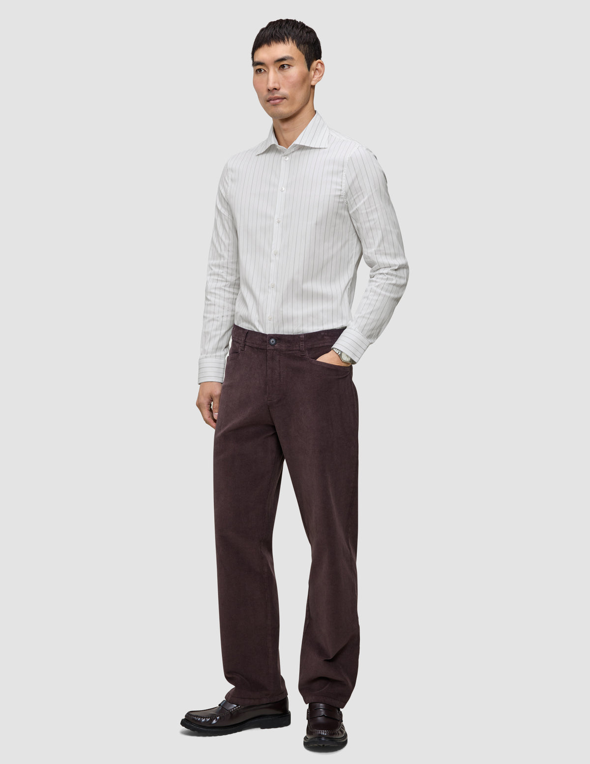 A man wearing an Elevated Shirt Slim Light Grey Striped shirt, dark brown trousers, and dark loafers.