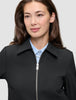 A minimalist black Essential Short Zip Jacket worn over a light blue button-down shirt.