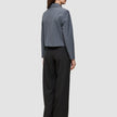 A woman viewed from behind, wearing an Essential Short Zip Jacket Dark Grey Melange and black wide-leg trousers.
