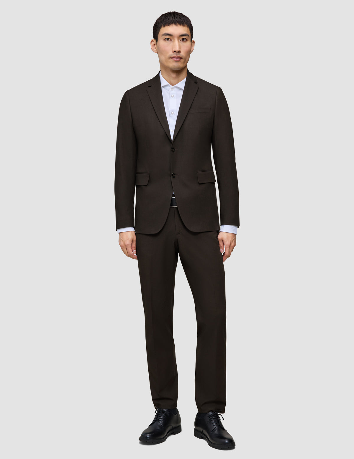 A man wears a Motion Blazer Regular Cognac over a white collared shirt and black dress shoes, reflecting a clean Scandinavian design.