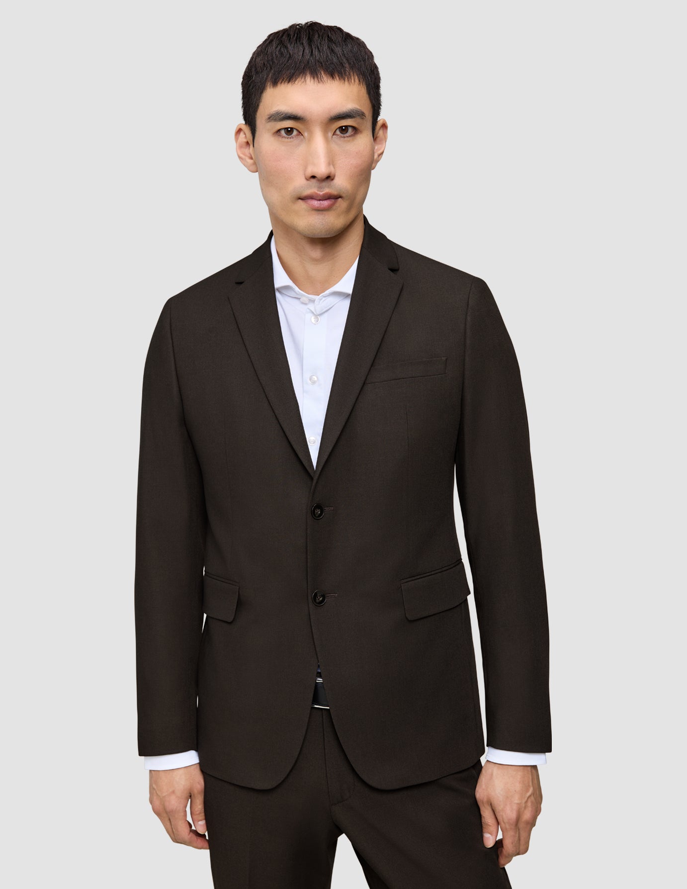 A man wearing a Motion Blazer Regular Cognac, a tailored, dark brown two-button blazer with 360° stretch over a white collared shirt.