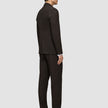 A man viewed from the side wearing a Motion Blazer Regular Cognac with matching dark brown trousers and black dress shoes.